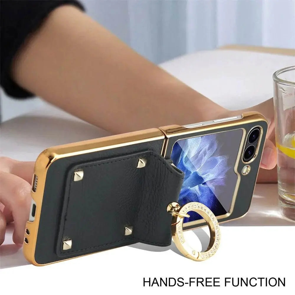 Smartphone with gold and black protective case featuring a leather hand strap and ring stand on table